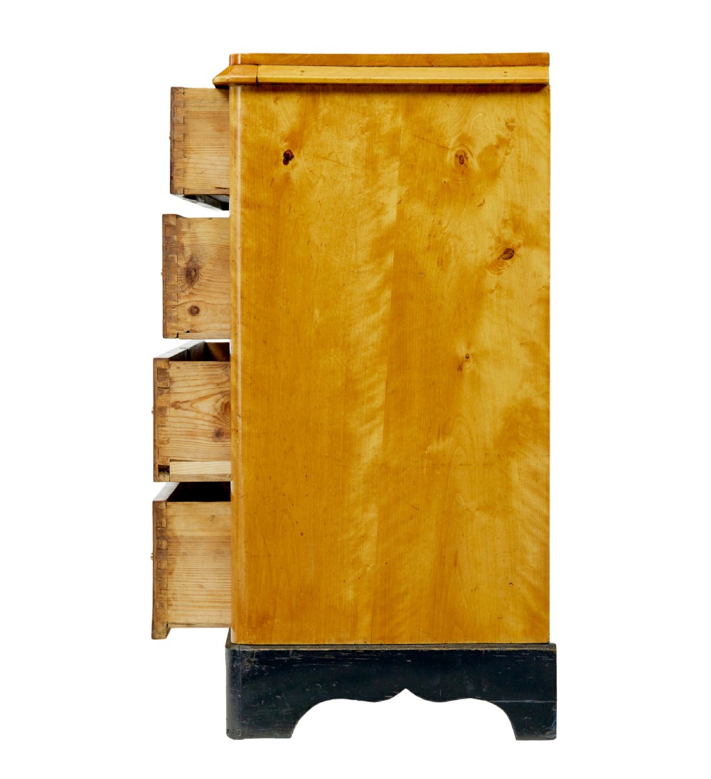 A 19th-century Swedish Empire Revival birch chest of drawers featuring four graduated drawers with metal handles, keyhole escutcheons, and a dark ebonised plinth base. View IV