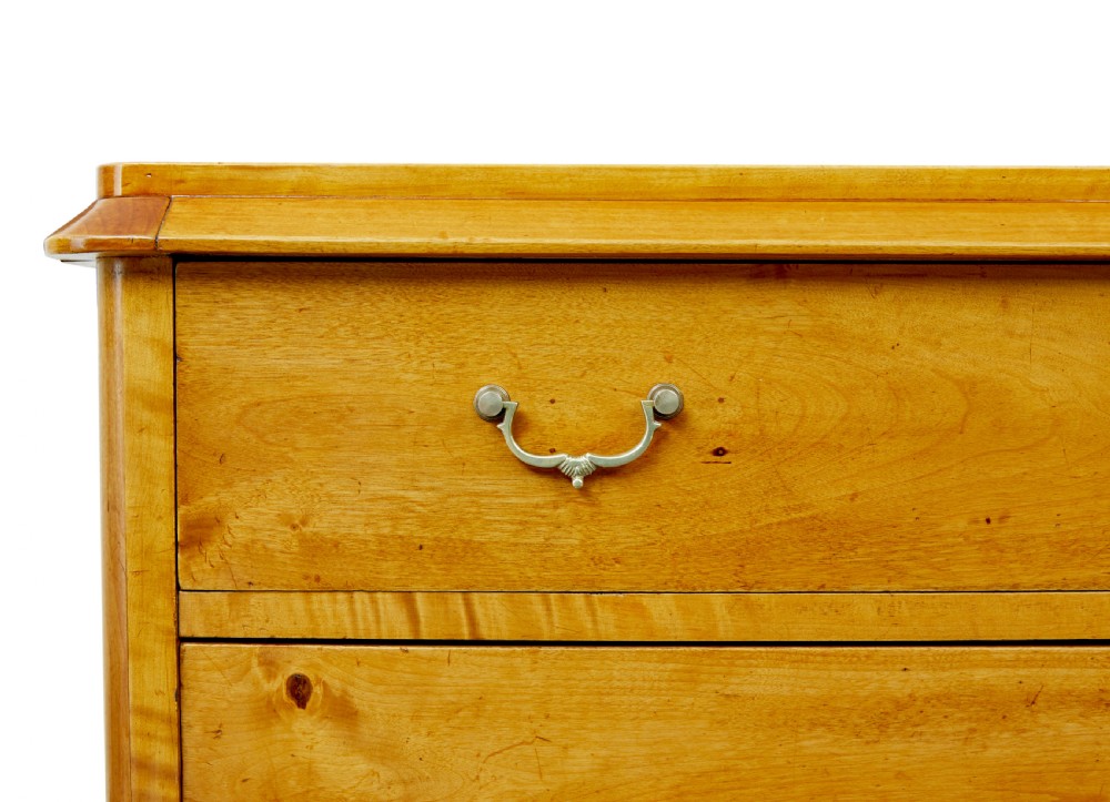 A 19th-century Swedish Empire Revival birch chest of drawers featuring four graduated drawers with metal handles, keyhole escutcheons, and a dark ebonised plinth base. View VII