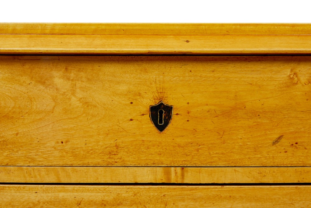 A 19th-century Swedish Empire Revival birch chest of drawers featuring four graduated drawers with metal handles, keyhole escutcheons, and a dark ebonised plinth base. View VIII