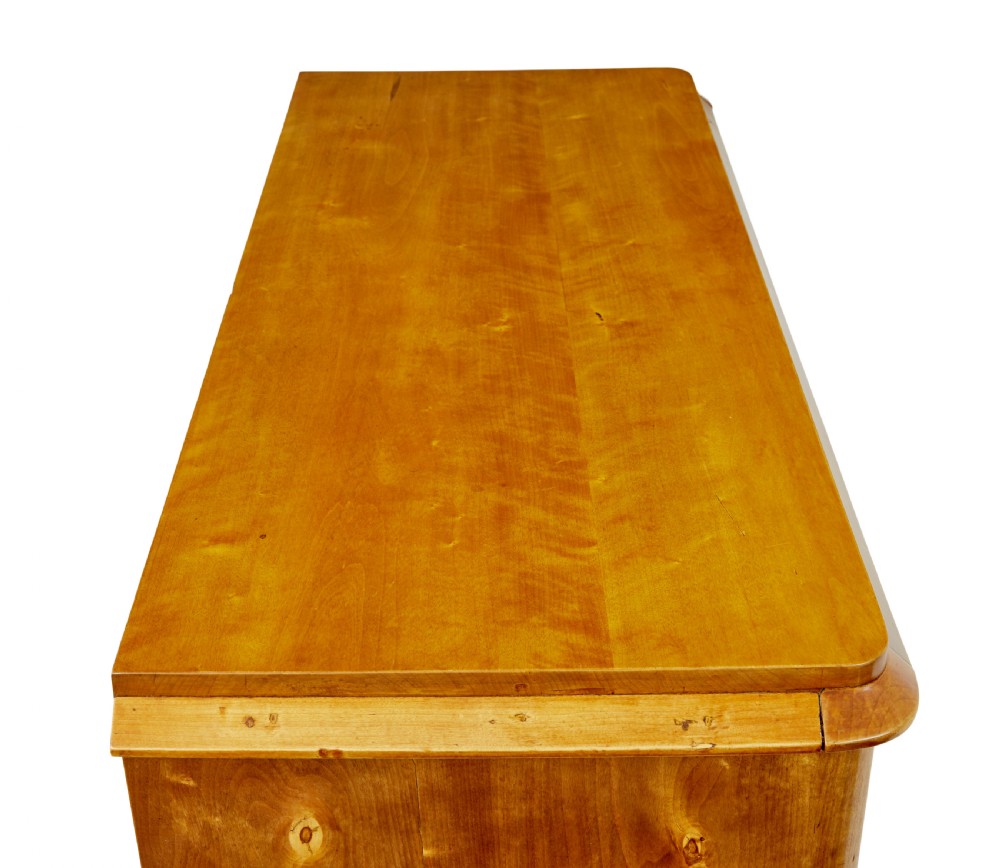 A 19th-century Swedish Empire Revival birch chest of drawers featuring four graduated drawers with metal handles, keyhole escutcheons, and a dark ebonised plinth base. View IX