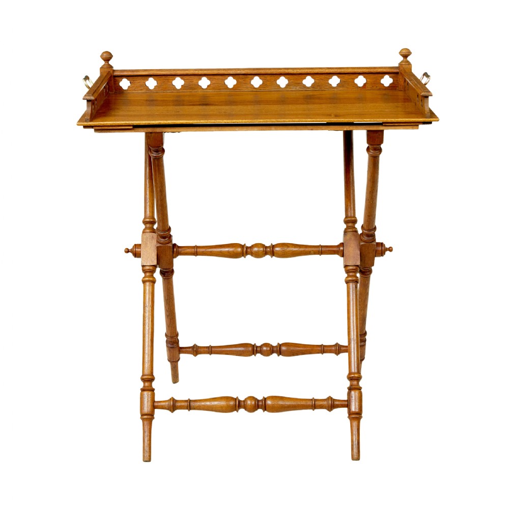 A 19th-century oak butlers tray featuring a trefoil pierced gallery border and brass handles resting on a folding X-frame stand. View V