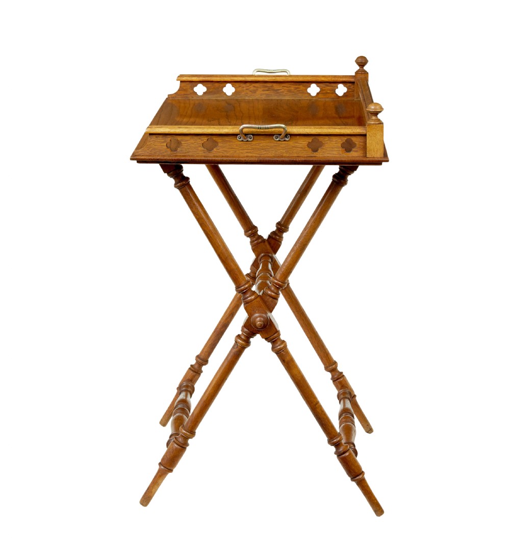A 19th-century oak butlers tray featuring a trefoil pierced gallery border and brass handles resting on a folding X-frame stand. View VI