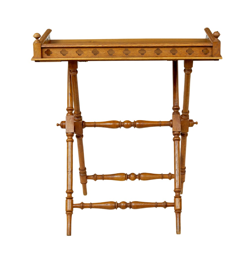 A 19th-century oak butlers tray featuring a trefoil pierced gallery border and brass handles resting on a folding X-frame stand. View VII