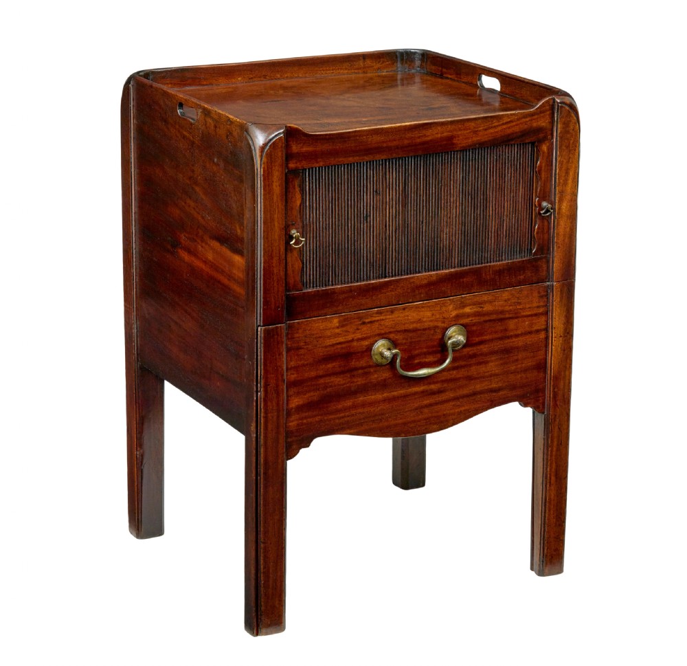 A 19th-century Georgian mahogany bedside table featuring a gallery top with hand-holds, a sliding tambour door, and a drawer with a brass handle.