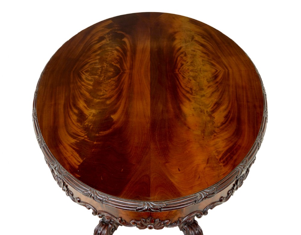An antique 19th-century oval mahogany centre table featuring a carved apron, a central turned pedestal stem, and a carved four-legged base with scroll feet. View II