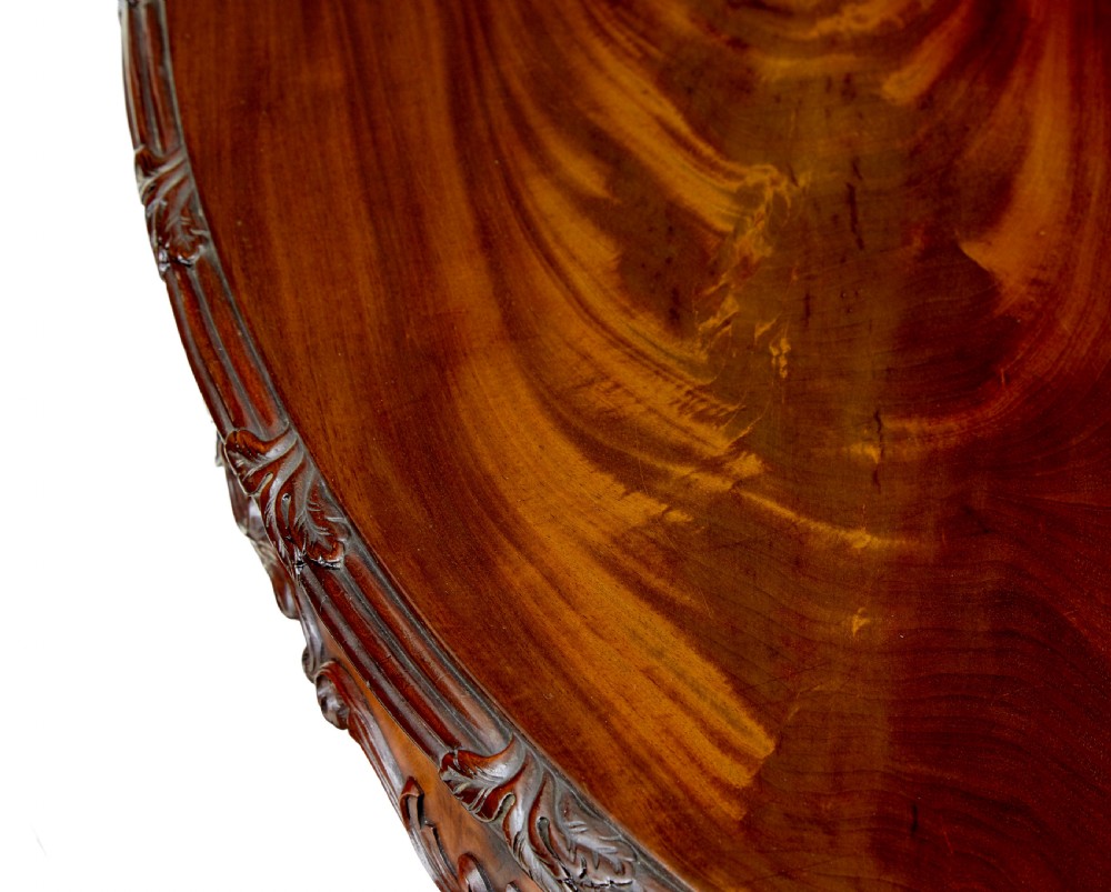 An antique 19th-century oval mahogany centre table featuring a carved apron, a central turned pedestal stem, and a carved four-legged base with scroll feet. View IV