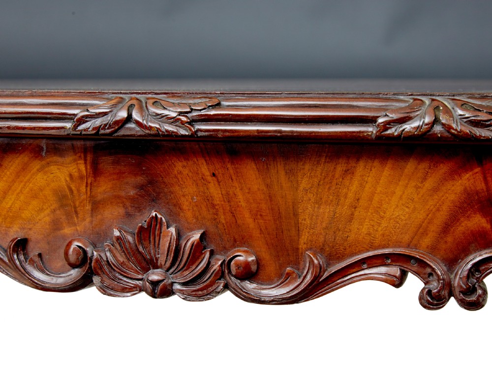 An antique 19th-century oval mahogany centre table featuring a carved apron, a central turned pedestal stem, and a carved four-legged base with scroll feet. View VI