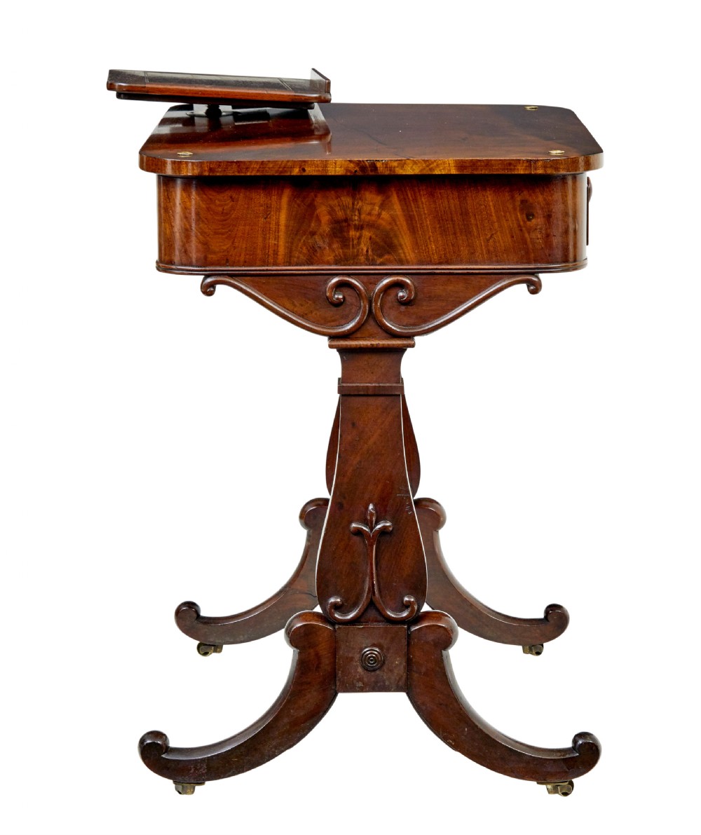 A mid-19th century dark mahogany writing table featuring an adjustable reading slope on top, a single open frieze drawer, scrolled side supports, turned stretcher, and brass castors. View VI