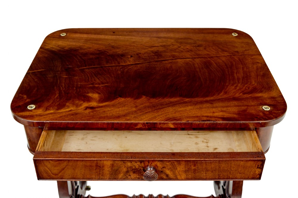 A mid-19th century dark mahogany writing table featuring an adjustable reading slope on top, a single open frieze drawer, scrolled side supports, turned stretcher, and brass castors. View IX