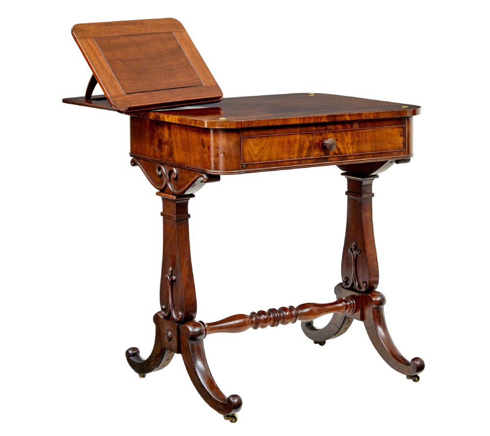 A mid-19th century dark mahogany writing table featuring an adjustable reading slope on top, a single open frieze drawer, scrolled side supports, turned stretcher, and brass castors. View X