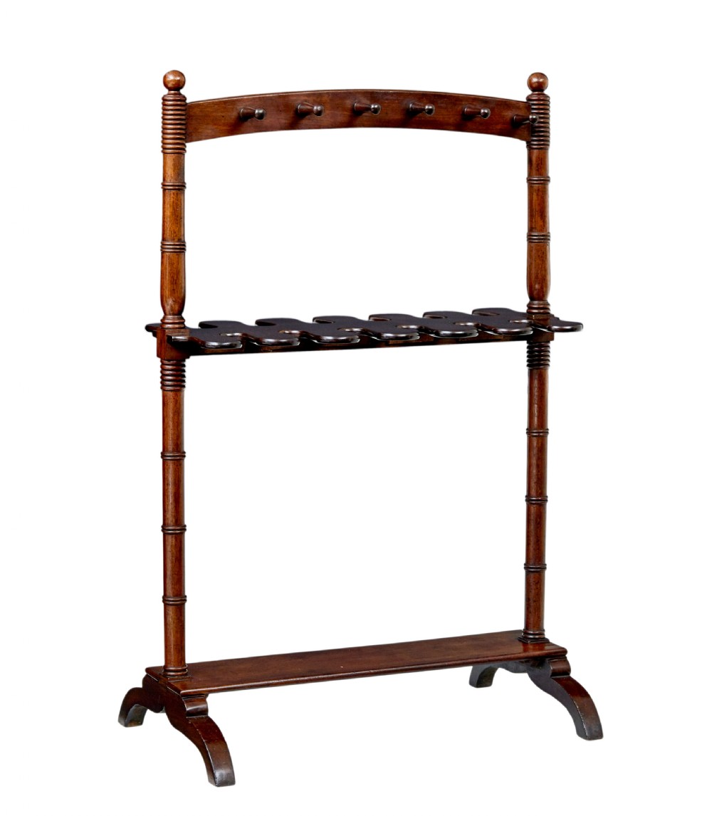 A mid-nineteenth-century dark mahogany wooden riding boot stand featuring turned side supports, upper hanging pegs, a notched central rack, and splayed feet.