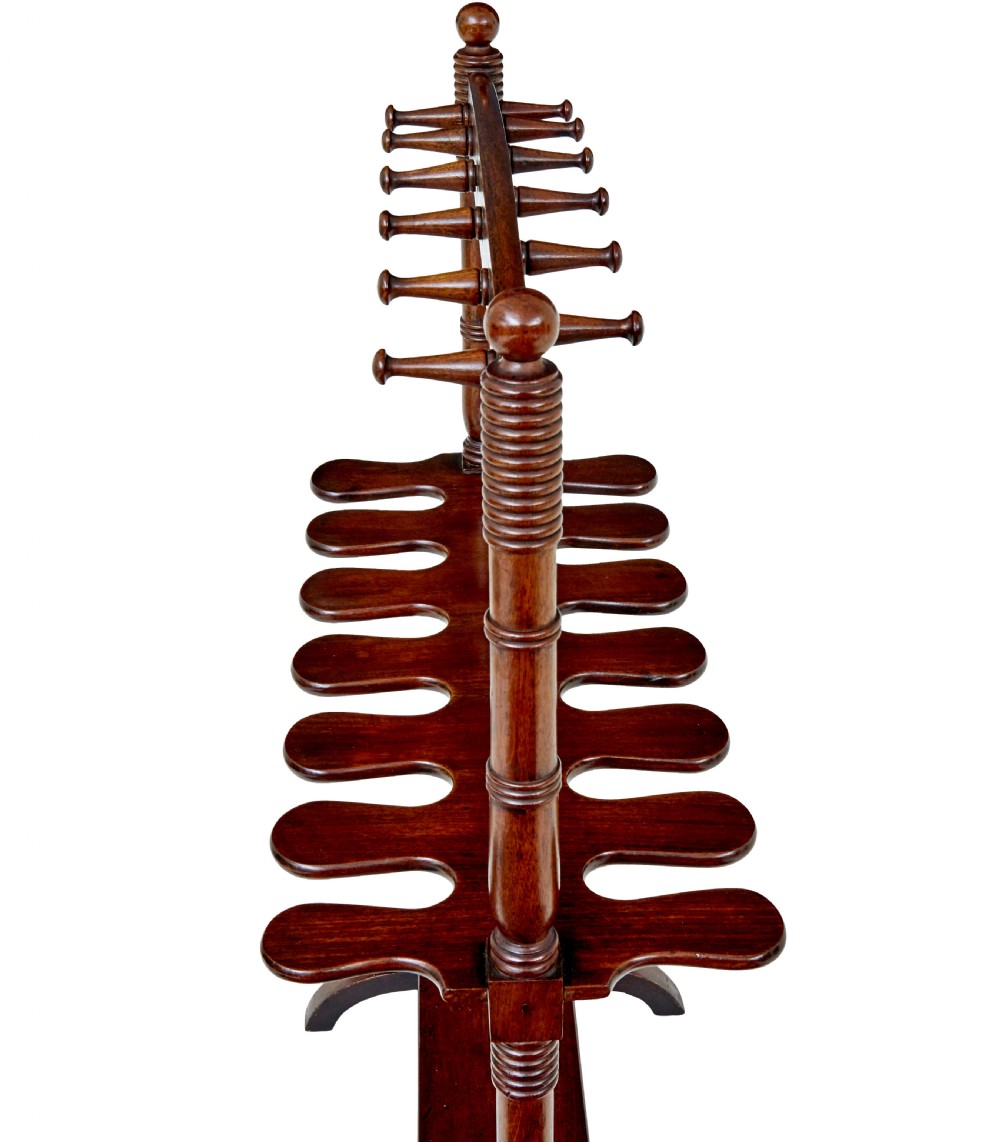 A mid-nineteenth-century dark mahogany wooden riding boot stand featuring turned side supports, upper hanging pegs, a notched central rack, and splayed feet. View II