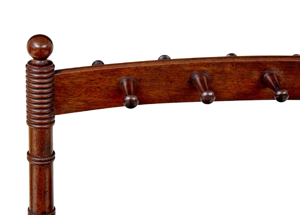 A mid-nineteenth-century dark mahogany wooden riding boot stand featuring turned side supports, upper hanging pegs, a notched central rack, and splayed feet. View III