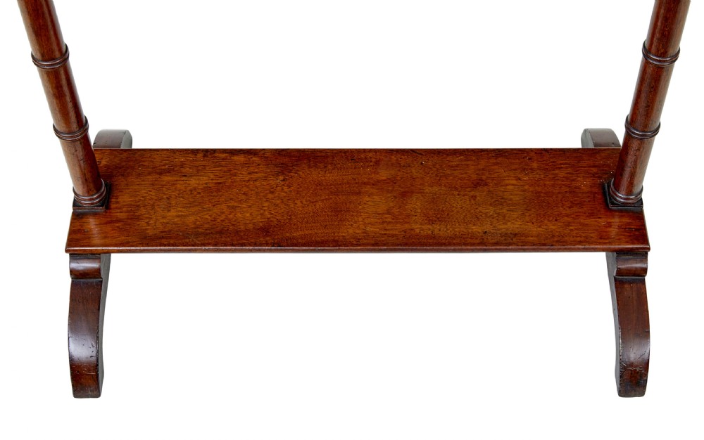 A mid-nineteenth-century dark mahogany wooden riding boot stand featuring turned side supports, upper hanging pegs, a notched central rack, and splayed feet. View V
