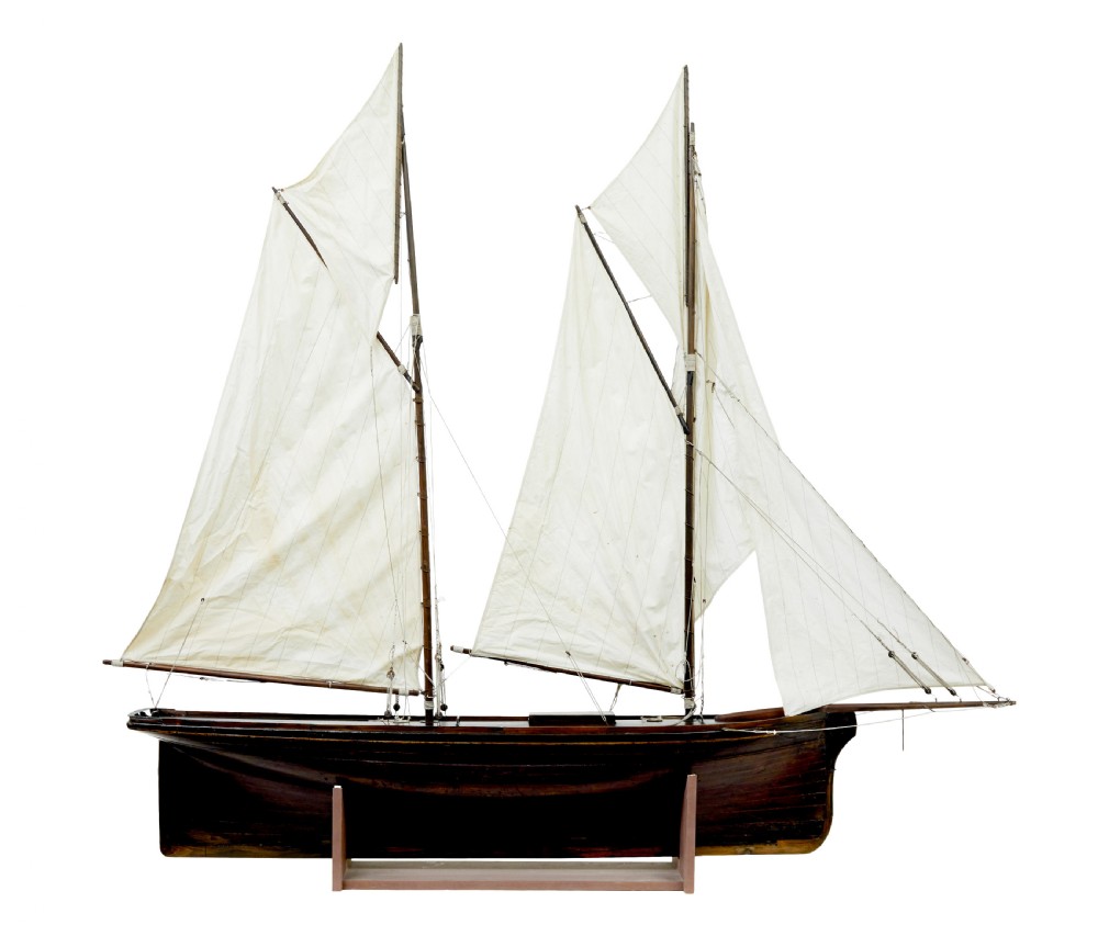 A late 19th-century wooden scale model of a two-masted sailing yacht with off-white sails mounted on a wooden stand. View III