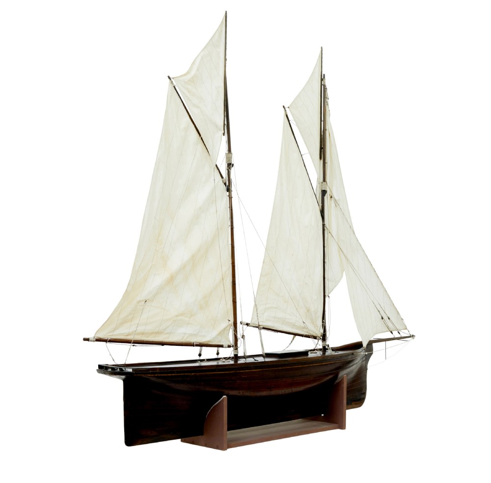 A late 19th-century wooden scale model of a two-masted sailing yacht with off-white sails mounted on a wooden stand. View V