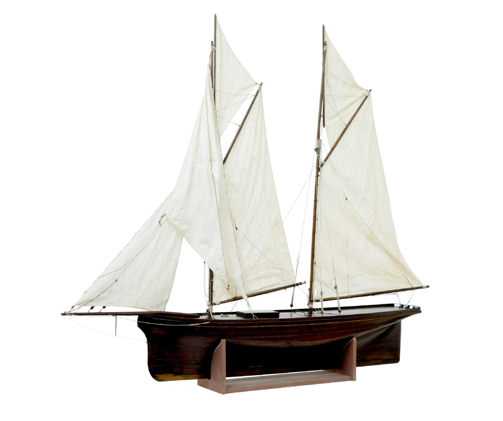 A late 19th-century wooden scale model of a two-masted sailing yacht with off-white sails mounted on a wooden stand. View VI