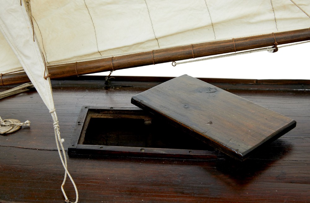 A late 19th-century wooden scale model of a two-masted sailing yacht with off-white sails mounted on a wooden stand. View IX