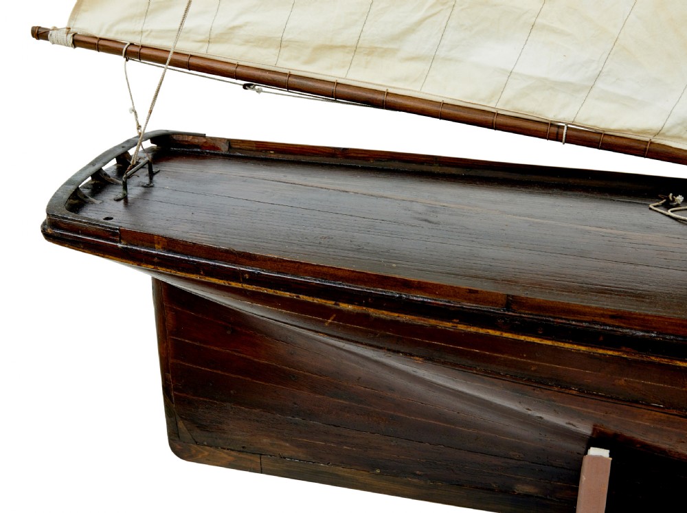 A late 19th-century wooden scale model of a two-masted sailing yacht with off-white sails mounted on a wooden stand. View XI