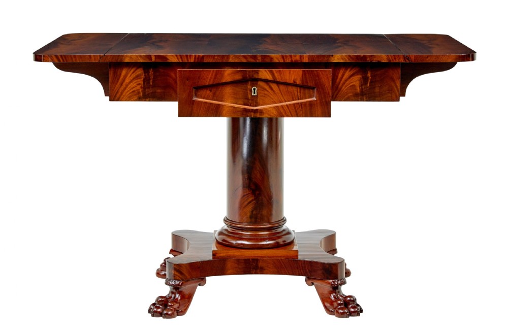 An early 20th-century Scandinavian Empire Revival mahogany sofa table featuring drop leaves, a single frieze drawer, a central cylindrical pedestal, and carved paw feet. View II
