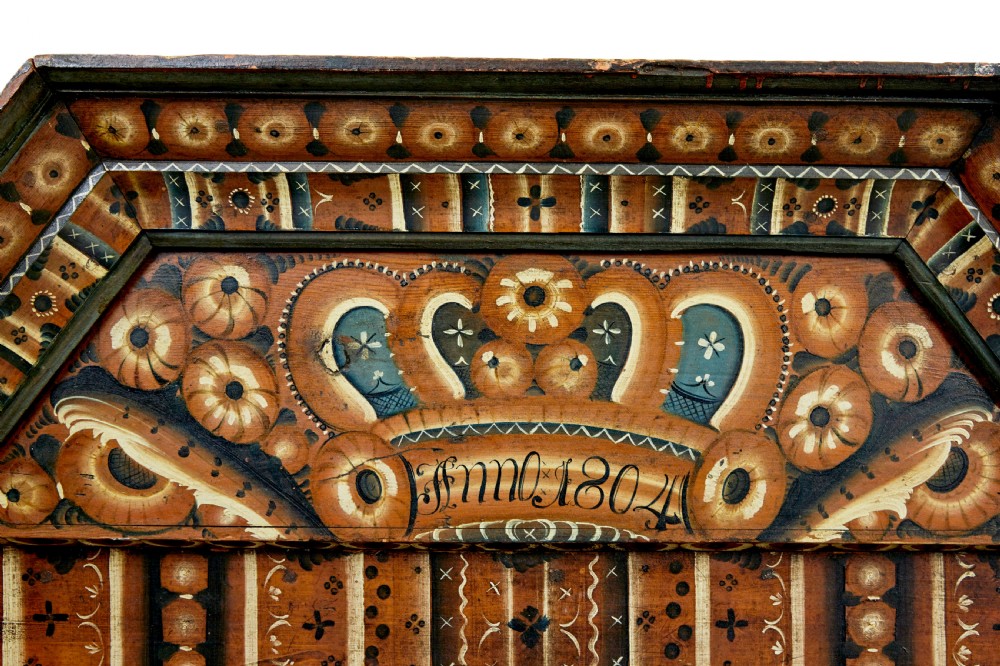 An early nineteenth-century Swedish painted wooden cupboard featuring floral folk art motifs, a shaped cornice dated 1804, and turned bun feet. View II
