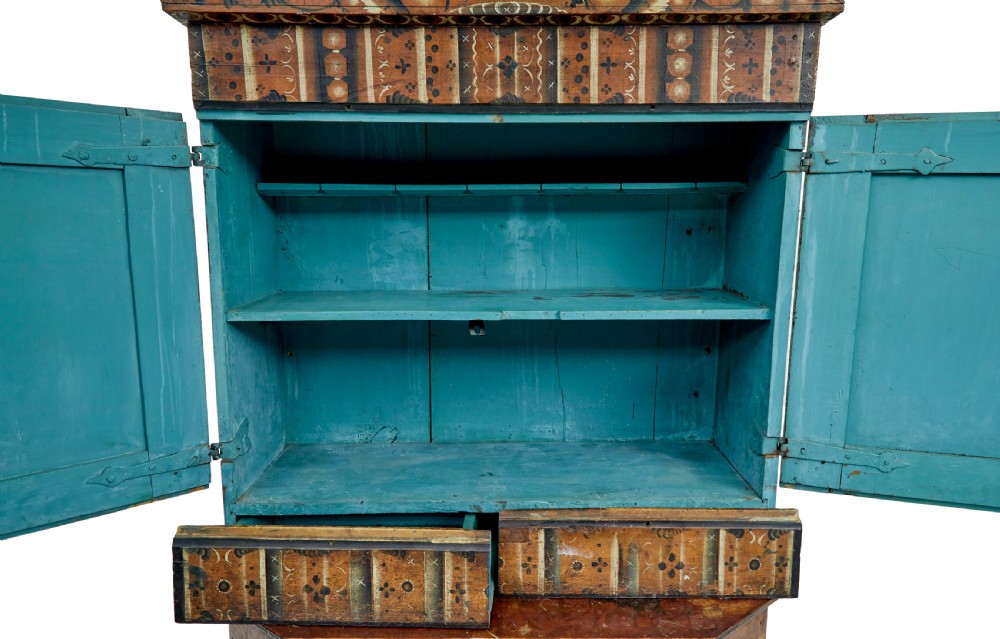 An early nineteenth-century Swedish painted wooden cupboard featuring floral folk art motifs, a shaped cornice dated 1804, and turned bun feet. View V
