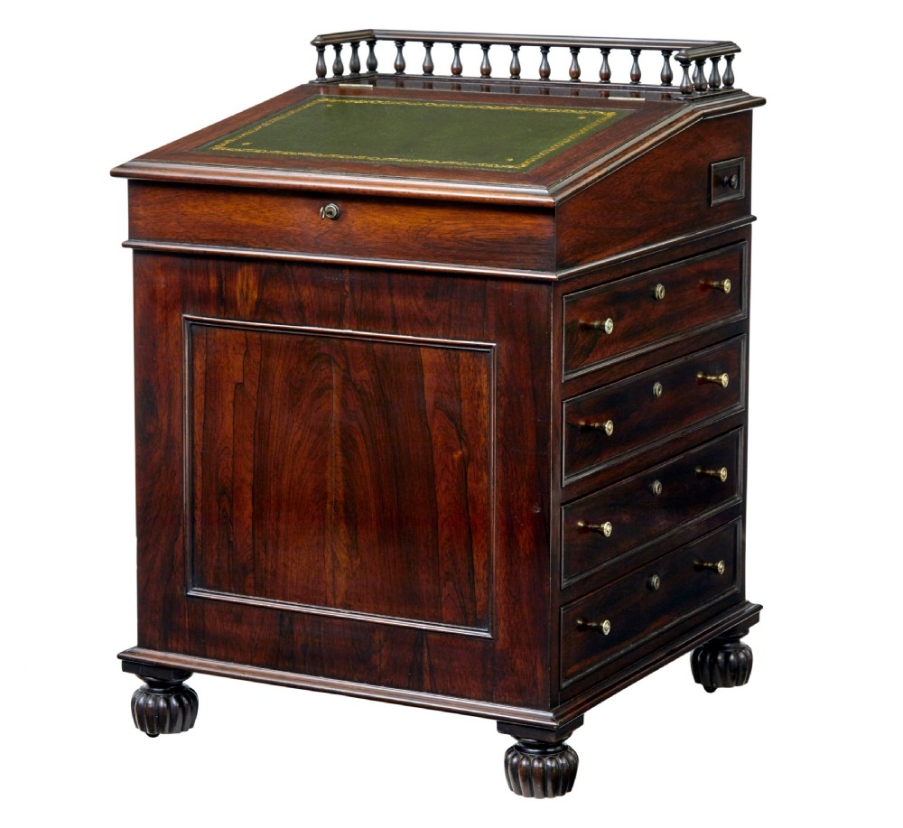 A mid-19th-century dark mahogany Davenport writing desk with a green leather gilded slant top, side drawers, and a balustrade gallery.