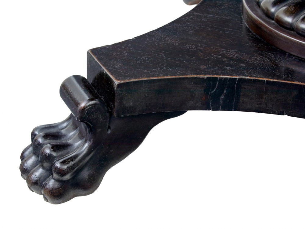 A 19th-century ebonised dark wood oval centre table featuring a fluted central pedestal and a quadform base supported by carved claw feet. View V
