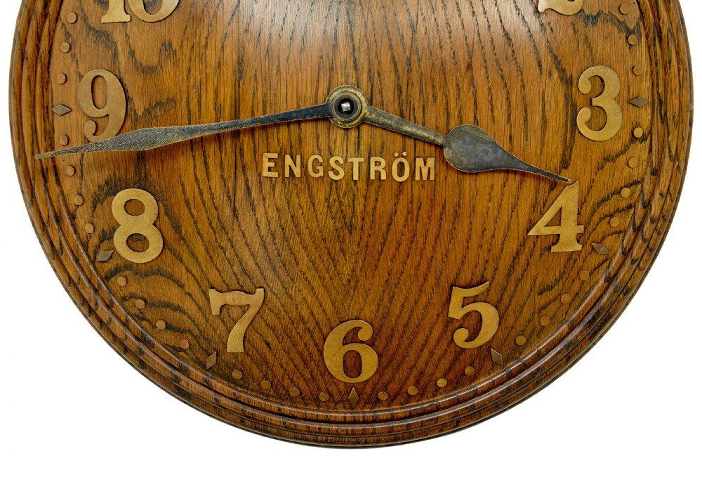 A circular Art Deco wall clock crafted from medium brown oak featuring applied brass Arabic numerals and metallic hands. View III