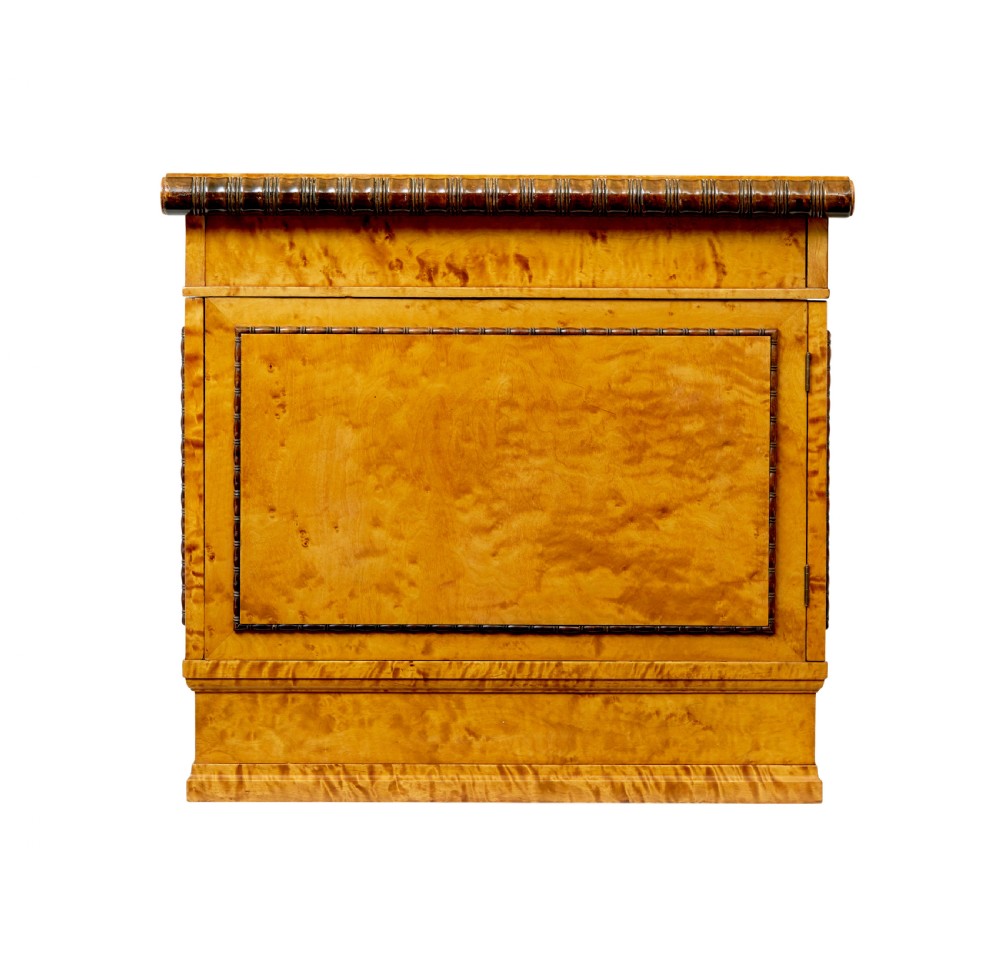 An Art Deco twin-pedestalled desk crafted from golden flame birch veneer featuring multiple drawers, cupboard doors, and decorative reeded borders. View VI