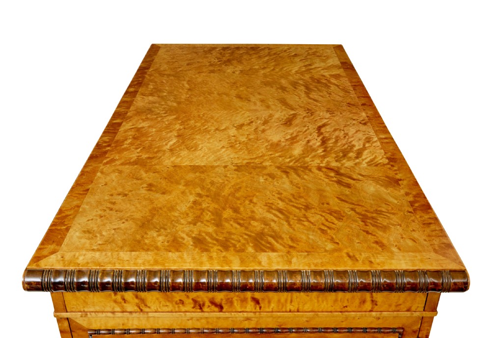 An Art Deco twin-pedestalled desk crafted from golden flame birch veneer featuring multiple drawers, cupboard doors, and decorative reeded borders. View VIII