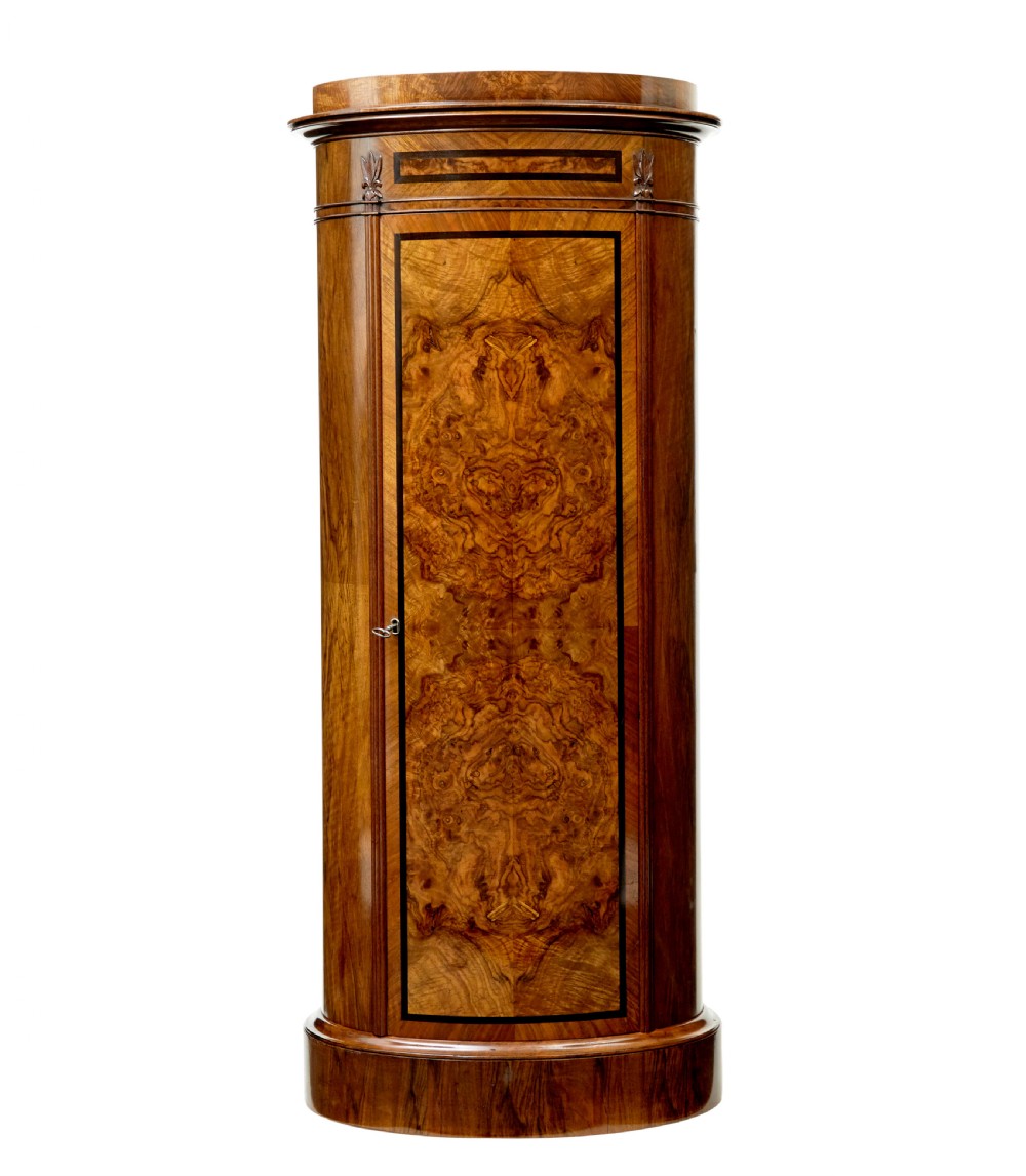 A 19th-century cylindrical burr walnut pedestal cupboard featuring geometric dark stringing and a single door with a key.