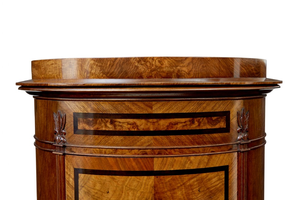 A 19th-century cylindrical burr walnut pedestal cupboard featuring geometric dark stringing and a single door with a key. View VI