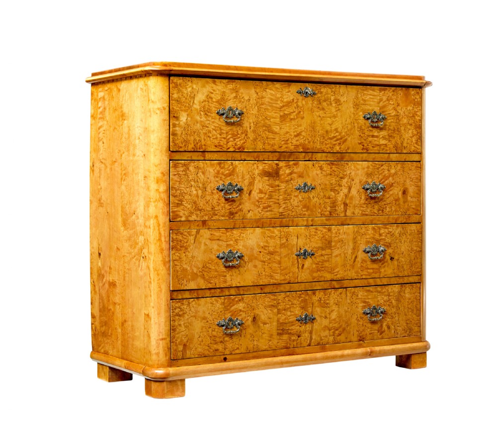 A mid-19th-century Swedish secretaire chest featuring highly figured burr birch veneers, four horizontal drawers, ornate brass handles, and block feet.