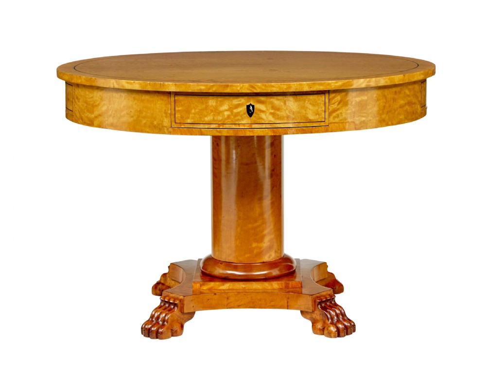 A circular 19th-century Swedish flame birch centre table featuring a single frieze drawer, a central cylindrical pedestal, and a shaped quadruped base resting on carved claw feet.