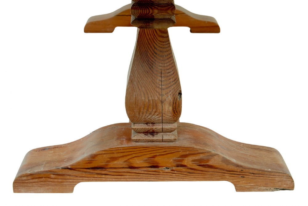 A nineteenth-century pine refectory dining table featuring a plank top, carved baluster supports, and a low central floor stretcher. View X