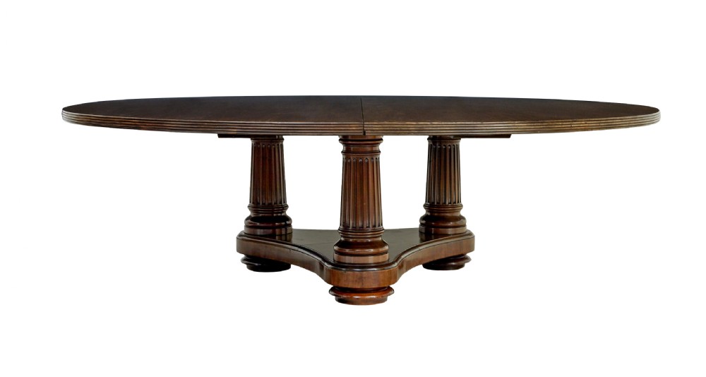 A mid 19th-century mahogany dining table featuring a broad oval top supported by three fluted column pedestals on a tri-form platform base.