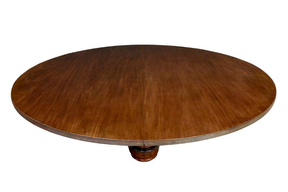 A mid 19th-century mahogany dining table featuring a broad oval top supported by three fluted column pedestals on a tri-form platform base. View III