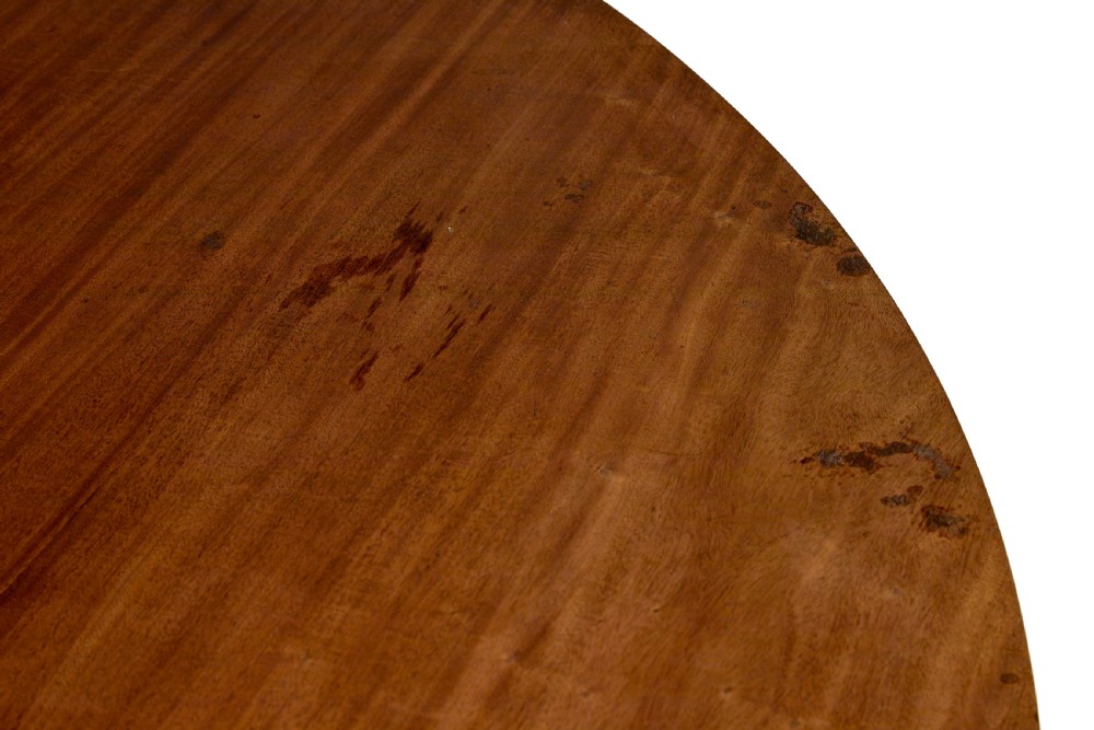 A mid 19th-century mahogany dining table featuring a broad oval top supported by three fluted column pedestals on a tri-form platform base. View V