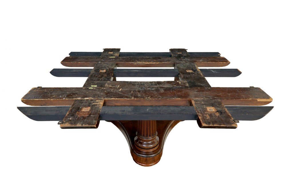 A mid 19th-century mahogany dining table featuring a broad oval top supported by three fluted column pedestals on a tri-form platform base. View VI
