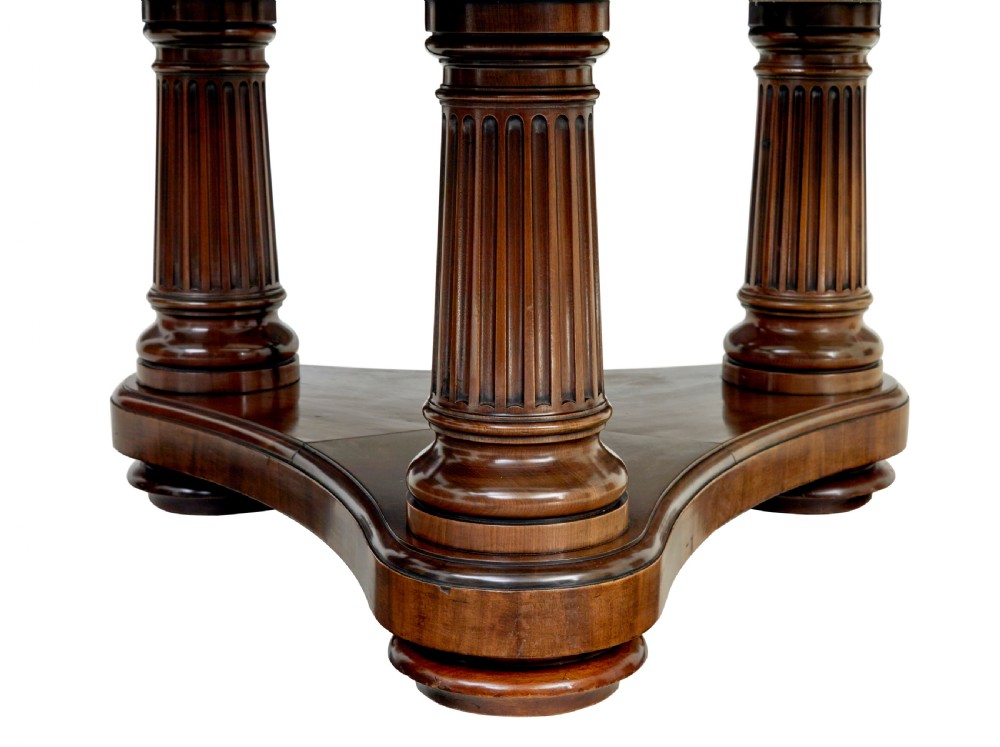 A mid 19th-century mahogany dining table featuring a broad oval top supported by three fluted column pedestals on a tri-form platform base. View VII