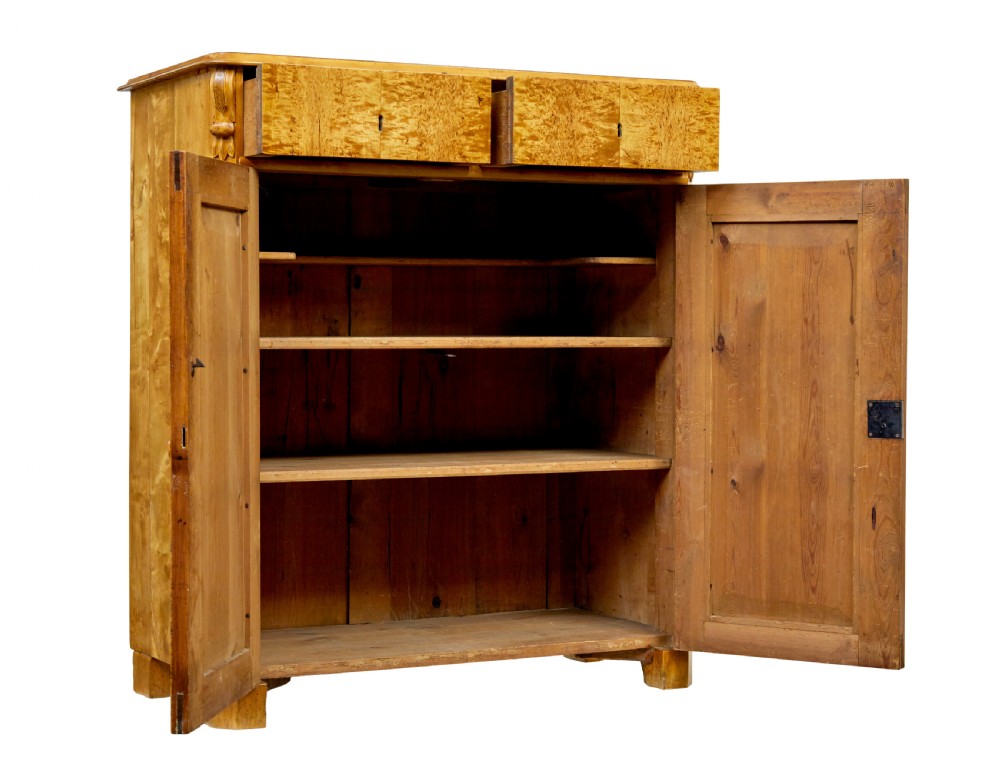 A nineteenth-century Swedish two-door cupboard constructed from golden tiger birch wood with two upper drawers and carved corner corbels. View II