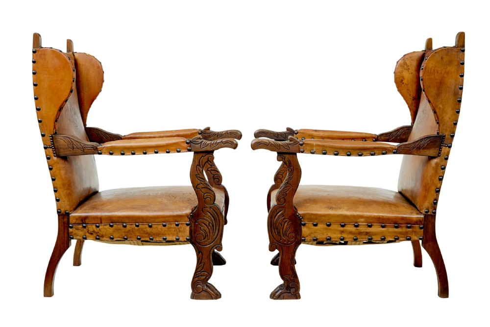 A pair of 19th-century oak armchairs featuring tan leather upholstery with central embossed medallions, brass stud trim, and carved supports. View III