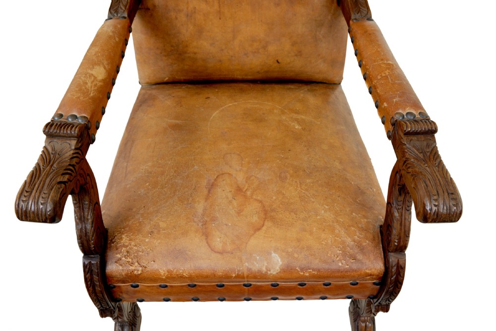 A pair of 19th-century oak armchairs featuring tan leather upholstery with central embossed medallions, brass stud trim, and carved supports. View VIII