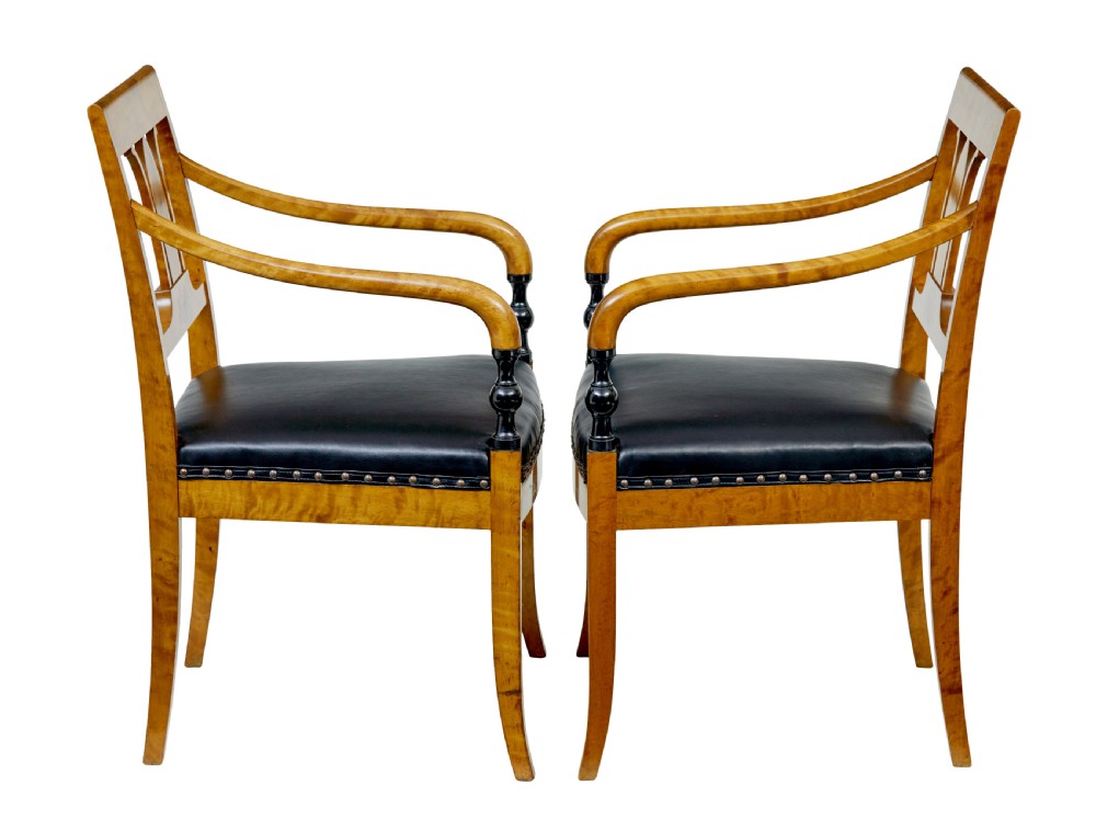 A pair of Art Deco Scandinavian birch armchairs featuring curved armrests, ebonised turned supports, inlaid back splats, and black leather studded seats. View IV