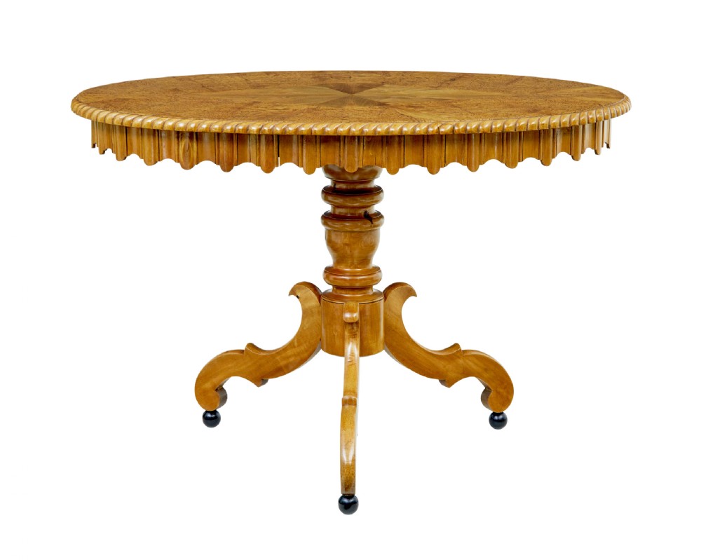 A 19th-century Swedish burr birch occasional table with a segmented veneer top, scalloped apron, turned central column, and tripod scroll feet.