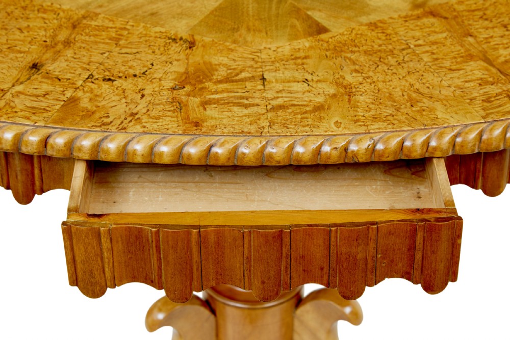 A 19th-century Swedish burr birch occasional table with a segmented veneer top, scalloped apron, turned central column, and tripod scroll feet. View VI