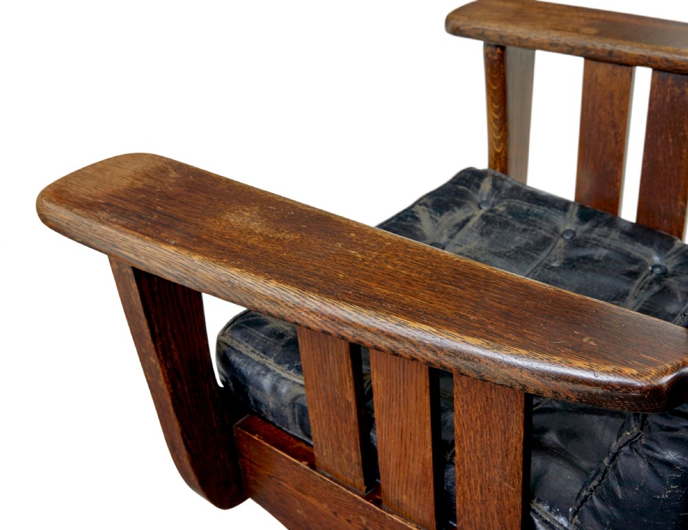 An early 20th-century dark oak platform rocking chair featuring button-tufted black leather cushions and carved front feet. View VIII