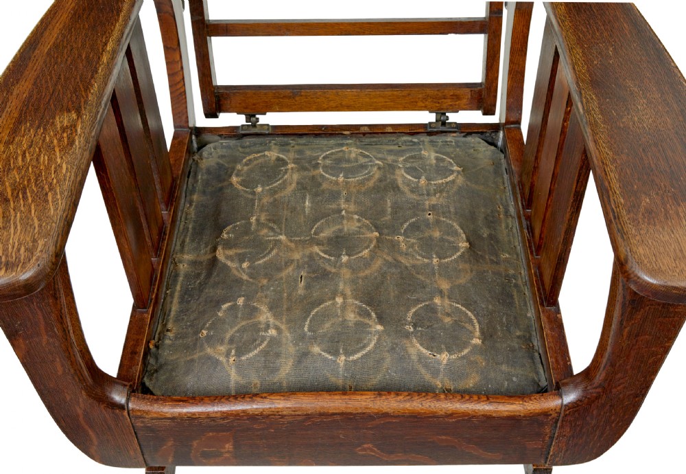 An early 20th-century dark oak platform rocking chair featuring button-tufted black leather cushions and carved front feet. View IX