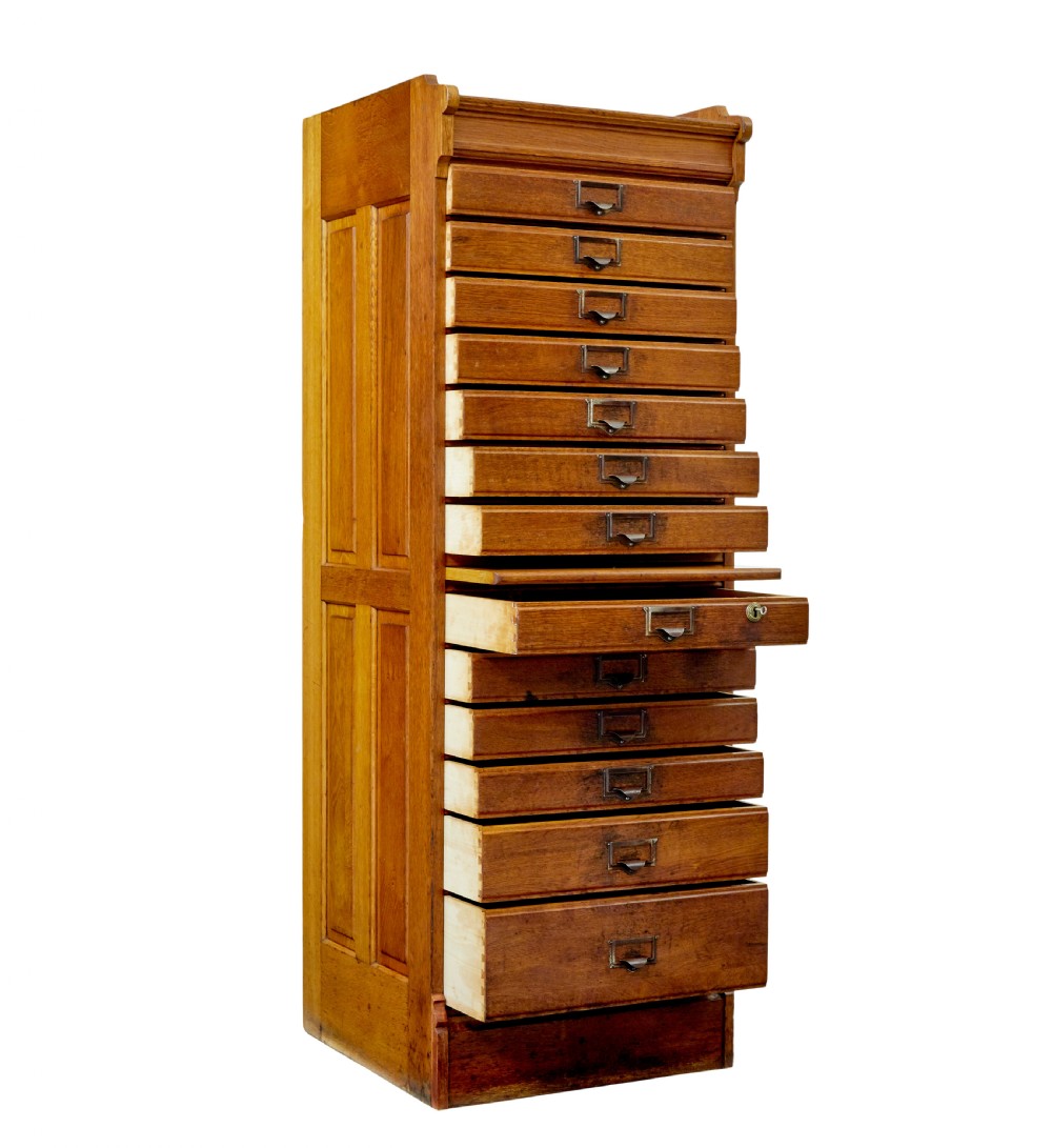 A tall early 20th-century solid oak filing chest featuring fourteen drawers with brass cup handles and label frames, flanked by paneled sides. View II